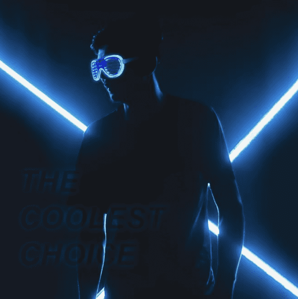 A man wearing goggles and standing in front of neon lights.